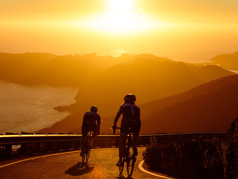 Two riders on road at sunset